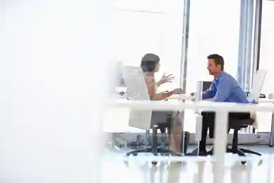 Two people sitting at a table in front of a laptop.