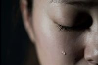 A close up of a person 's face with tears in their eyes.