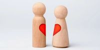 Two wooden figurines with a red heart on them.