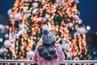 A person standing in front of a christmas tree.